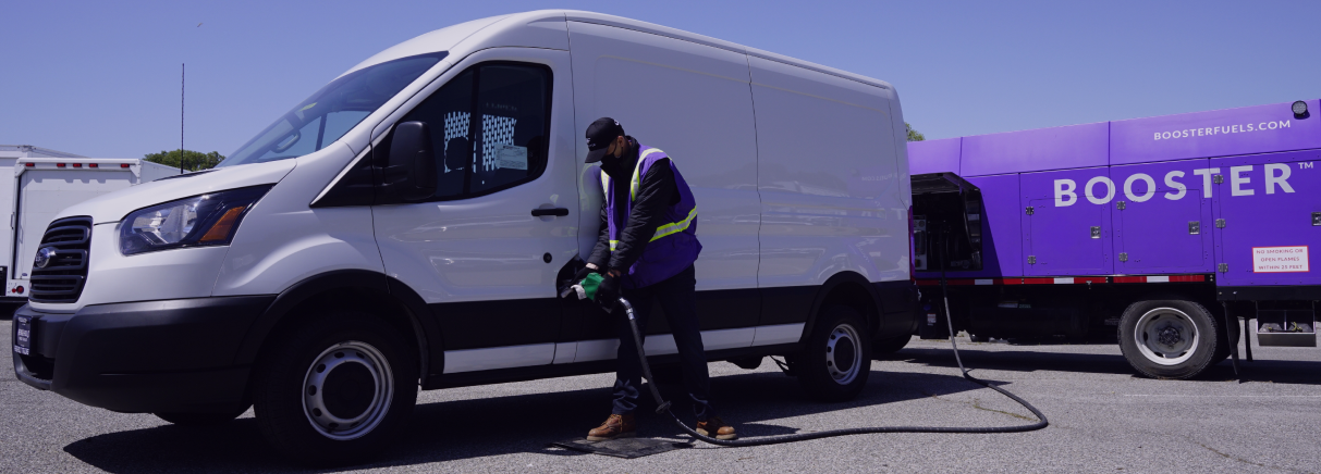 man fueling white van with purple tanker