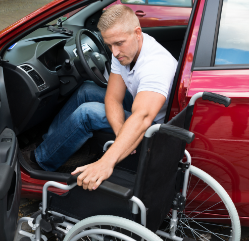 man with wheelchair exiting red car
