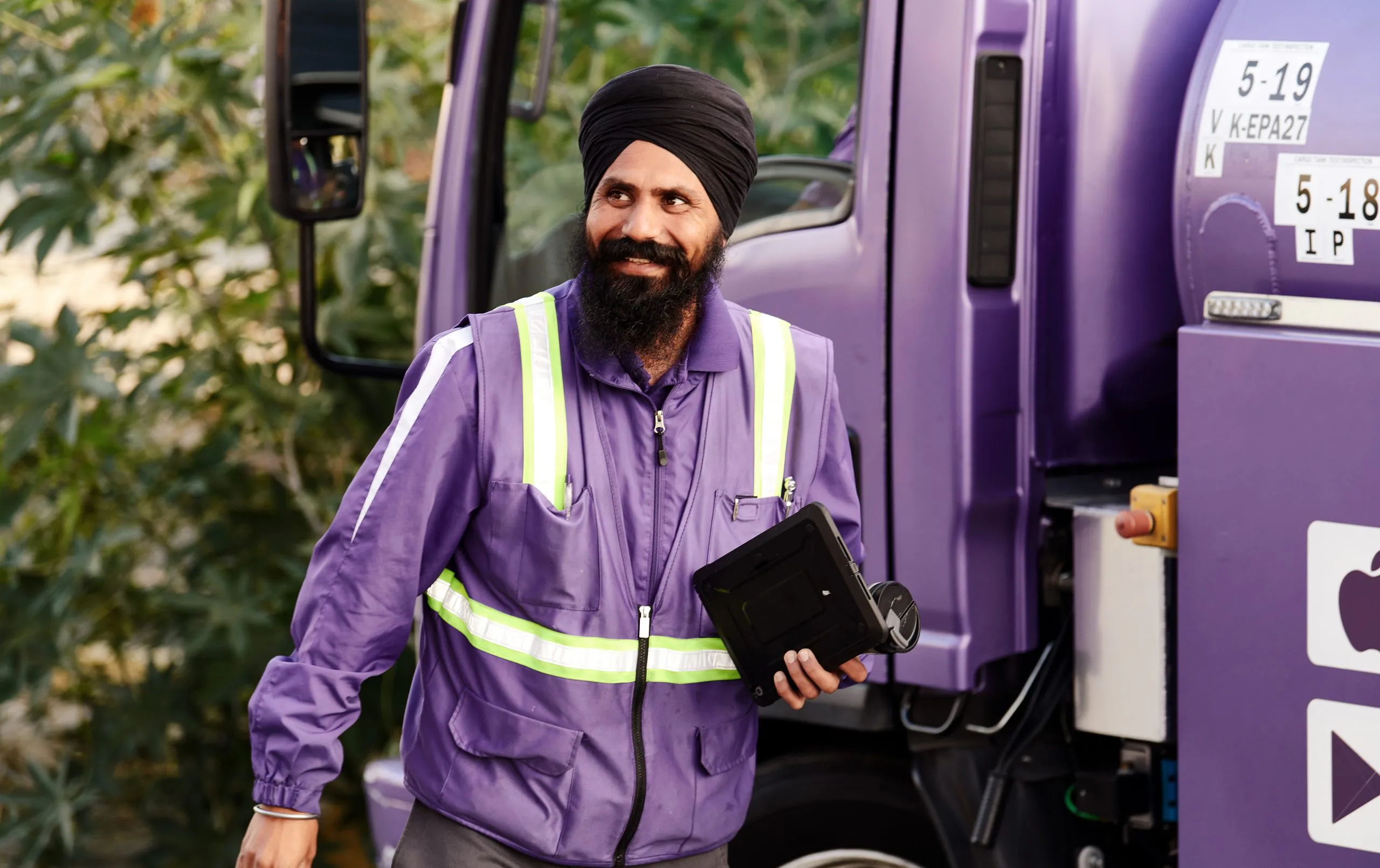 Smiling South Asian Booster service professional man beside truck