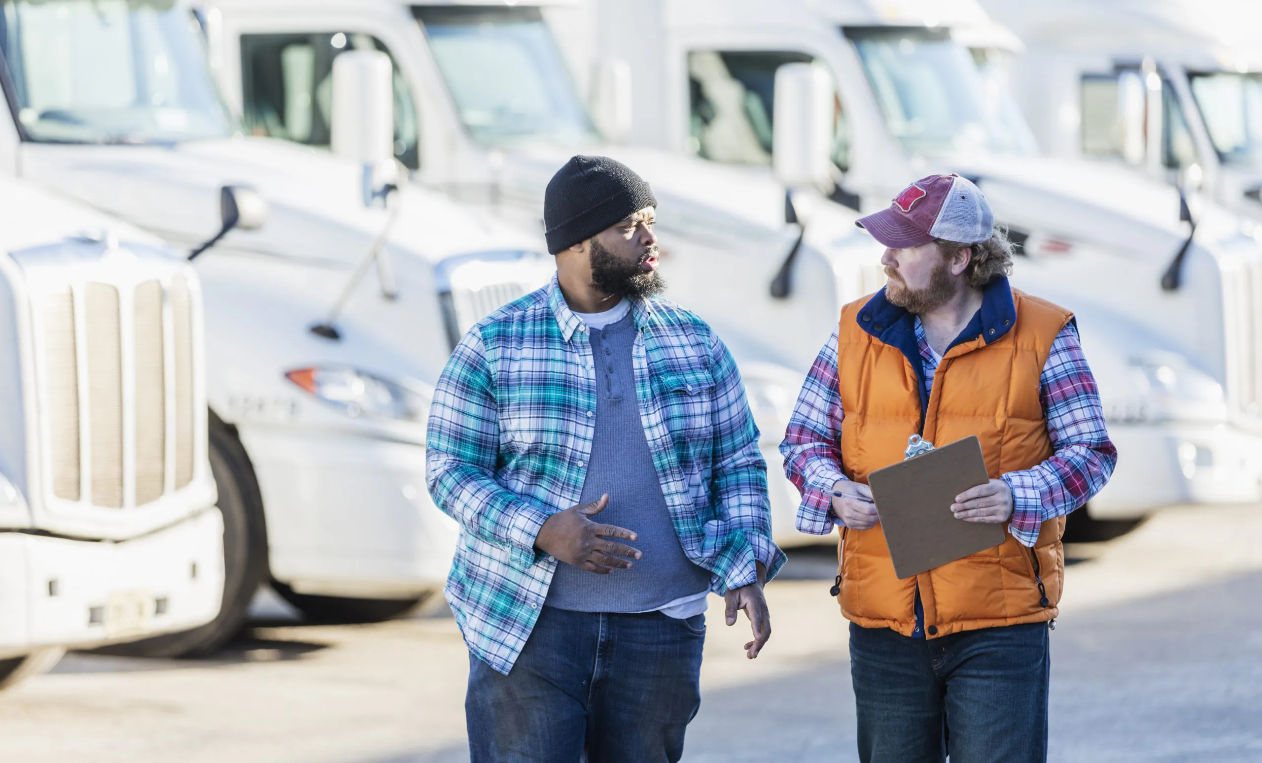 truck drivers in discussion with row of semi trucks behind