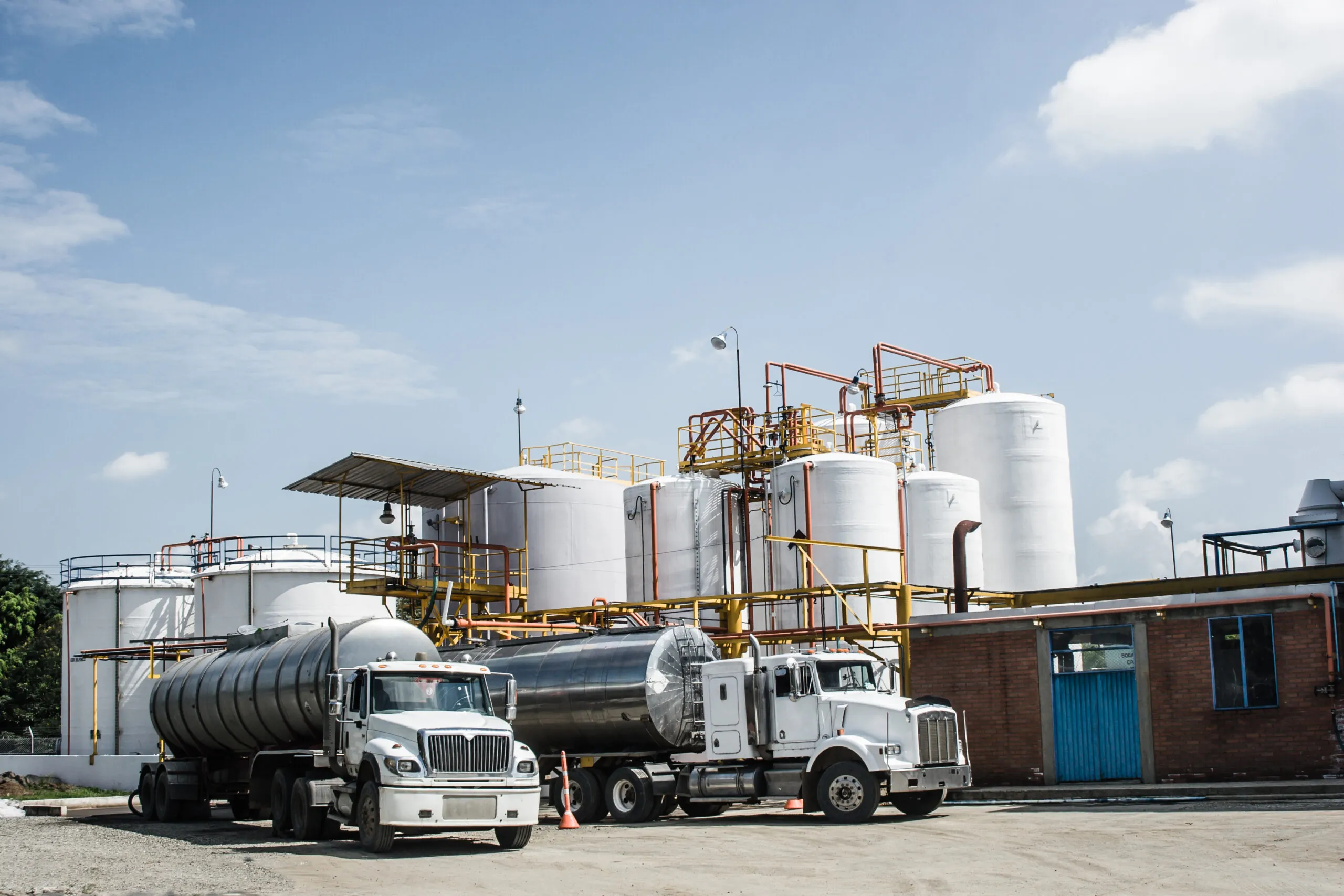 chemical storage tanks with 2 tanker trucks in foreground